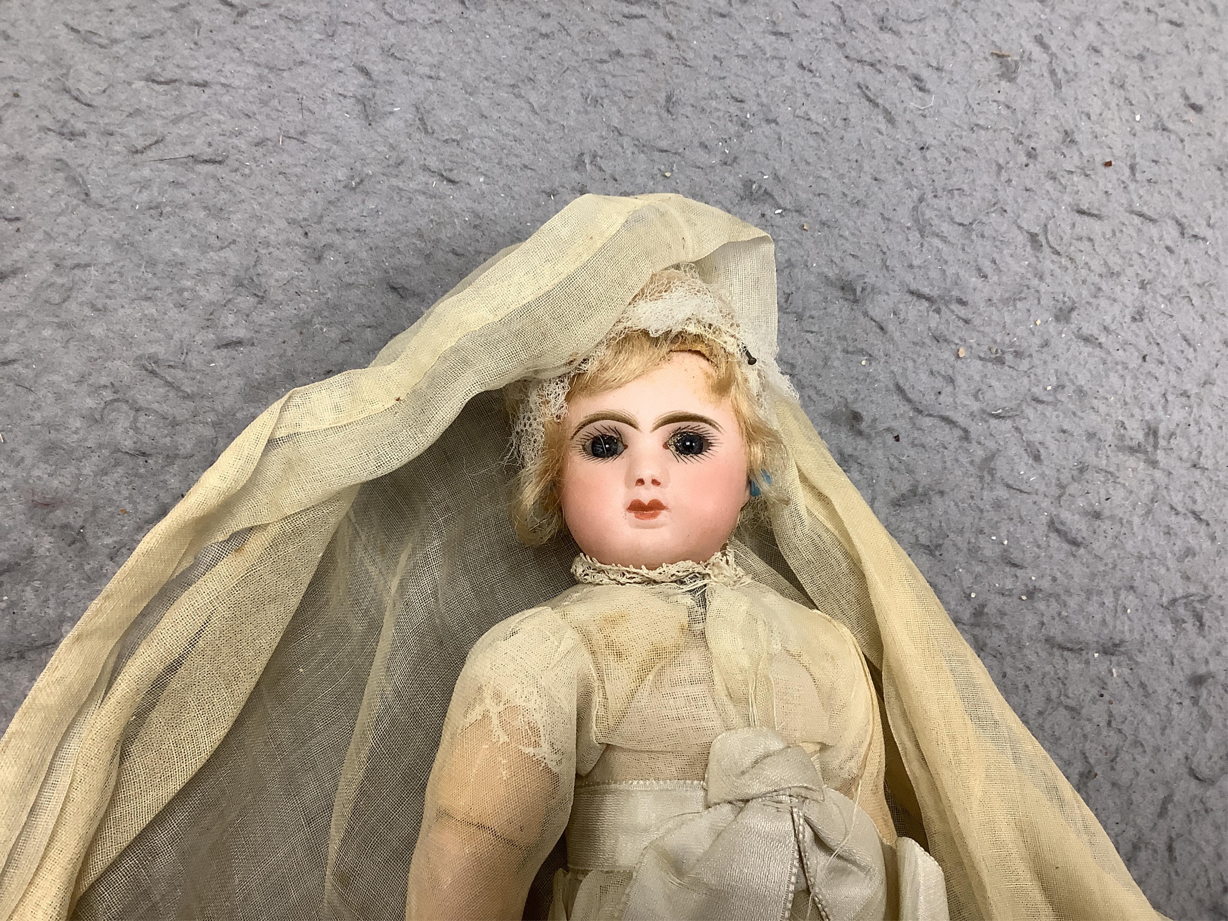 A Tête Jumeau bisque doll, closed mouth and paperweight eyes, jointed wood and composition body, two other French bisque dolls and assorted clothing, all contained within a three-layer wood and metal-bound cabin trunk, J